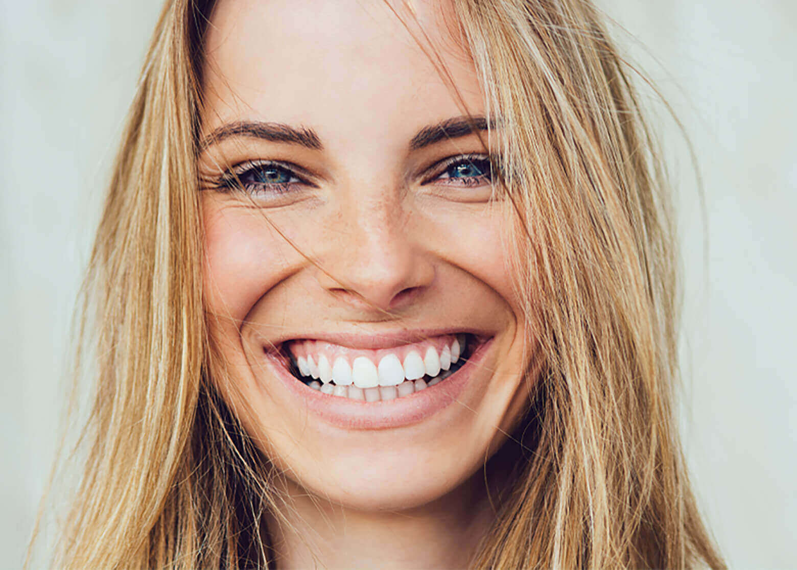 Blonde woman with white teeth smiling.