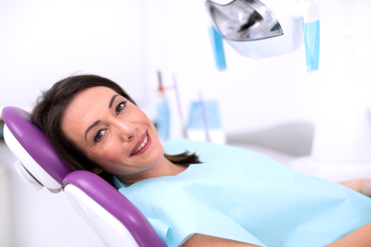 Smiling brunette woman in dental chair awaiting root canal therapy