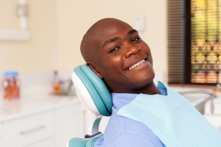 Smiling man in the dental chair or an exam and oral cancer screening.