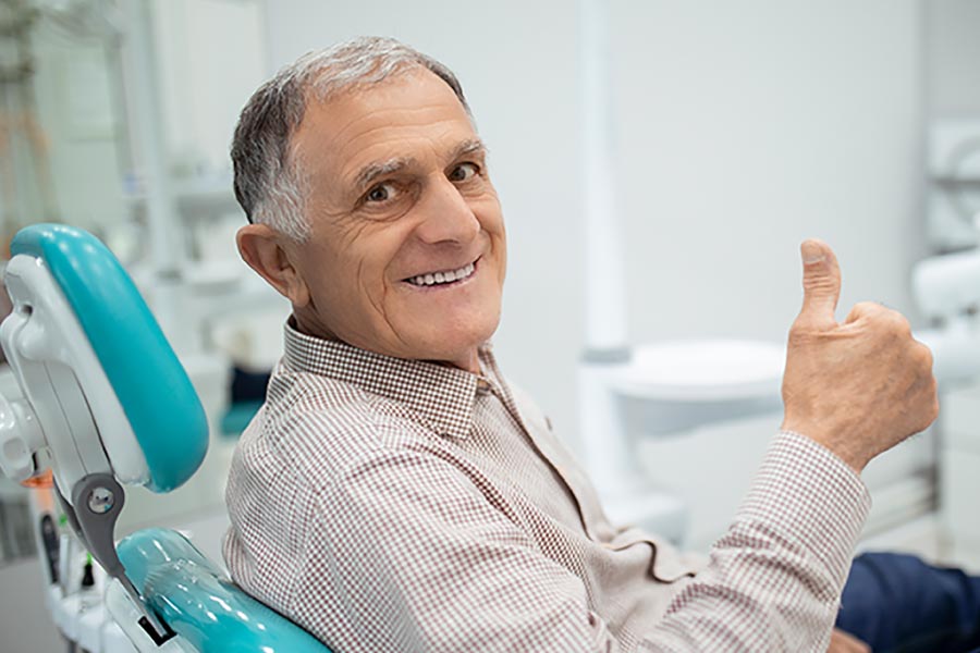 Senior man giving the thumbs up sign from the dental chair.